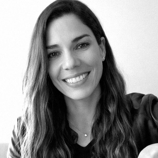 Mujer sonriente con cabello largo y oscuro, fondo blanco.